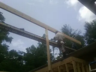 Carpenter setting a ridge beam over a new addition frame — Ice Dam Removal by Roofing Brothers in Clifton Springs