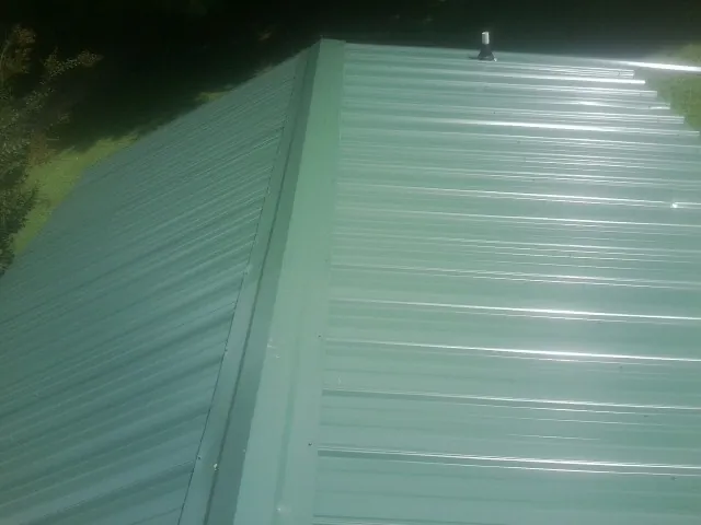 New green metal panels meeting at the ridge of a roof — Flat Roof Repair work by our crew in Clifton Springs