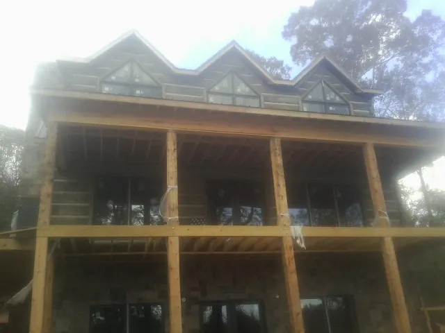Dormers and porch framing on a large log home under construction — Roof Coating work by our crew in Clifton Springs