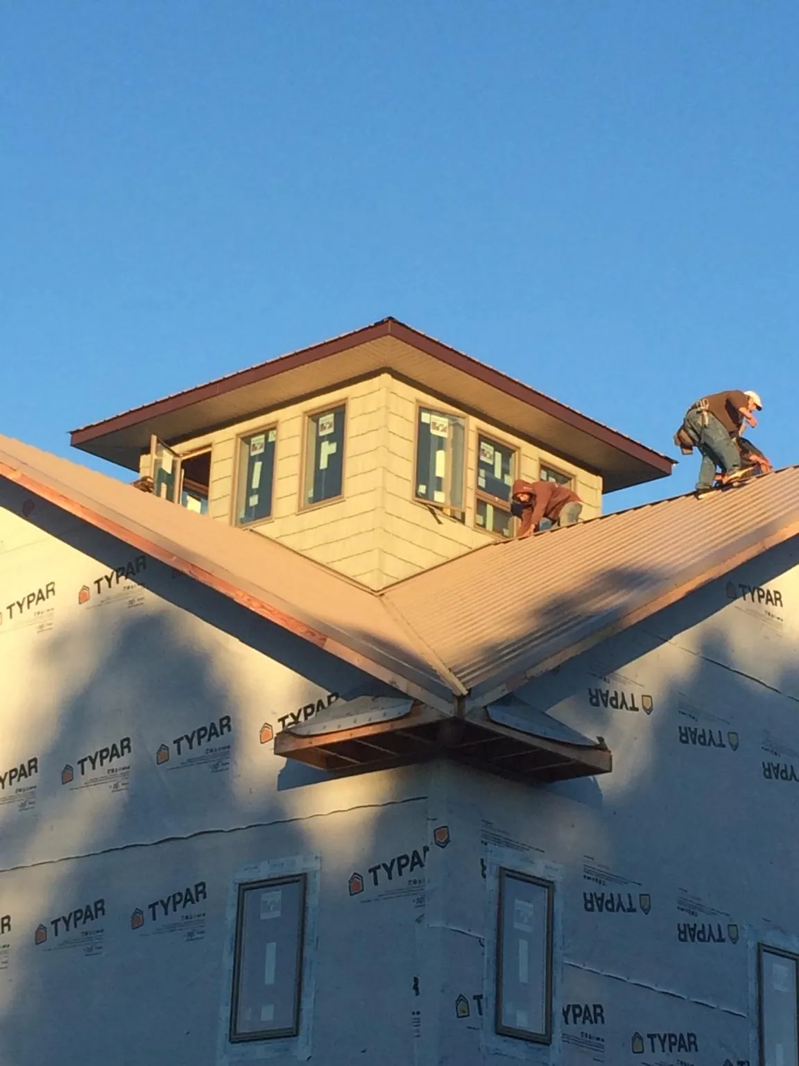Roofers working around a rooftop cupola on a new metal roof at sunset — Roof Waterproofing in Clifton Springs by Roofing Brothers